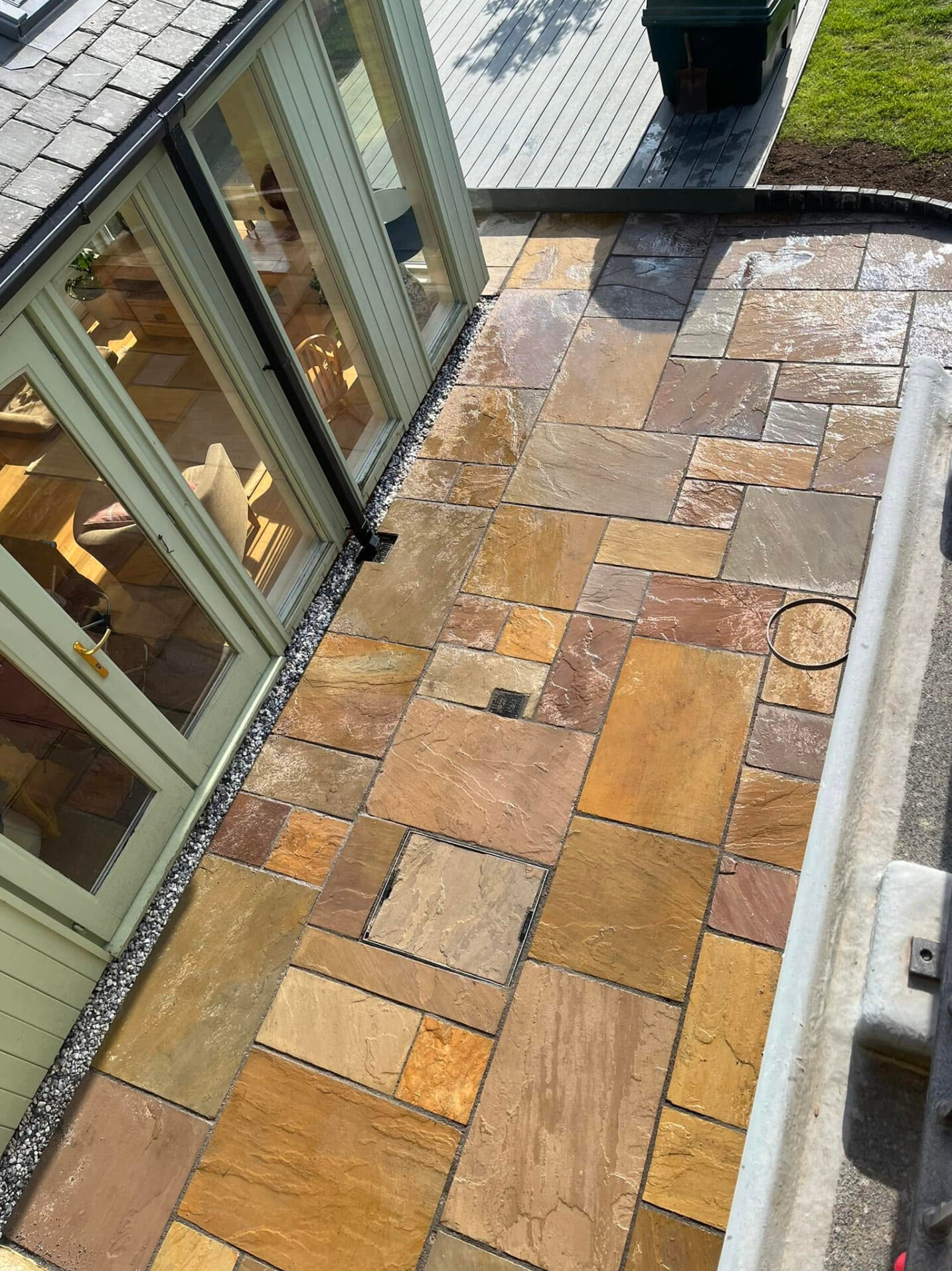 Warm-toned natural stone paving beside a conservatory