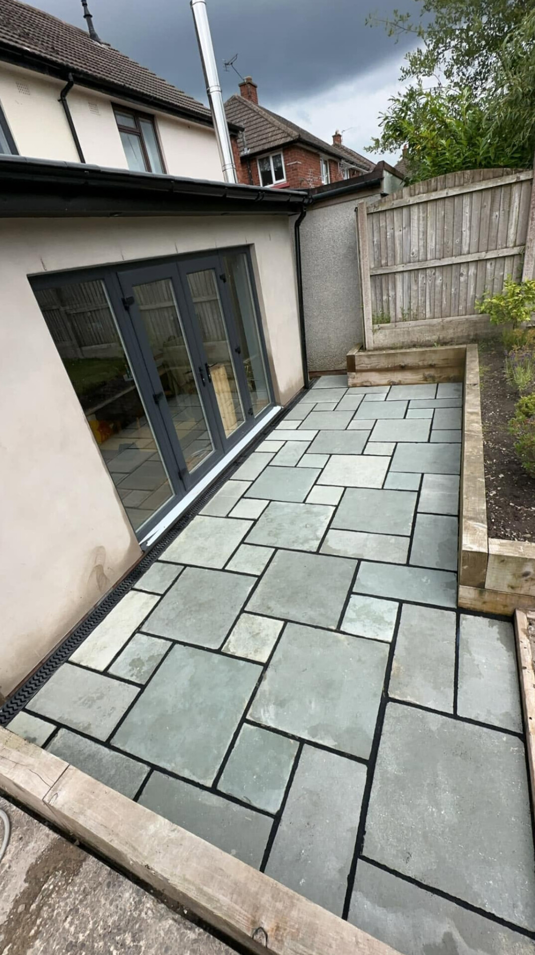 Contemporary grey stone paving laid alongside a property with bifold doors