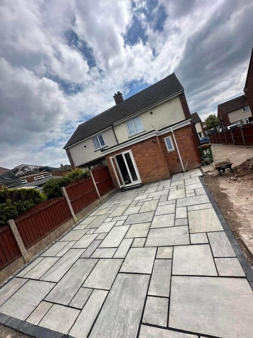 Large contemporary grey paved patio laid across a rear garden in Carlisle