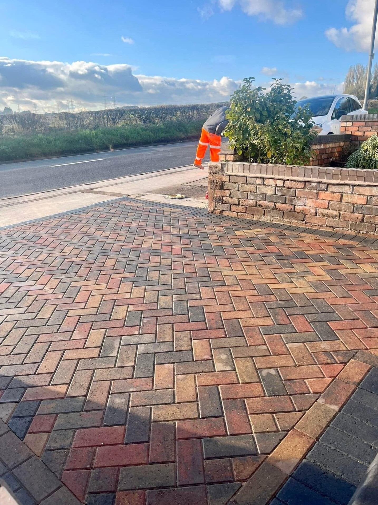 Multicoloured herringbone block-paved driveway with brick retaining wall