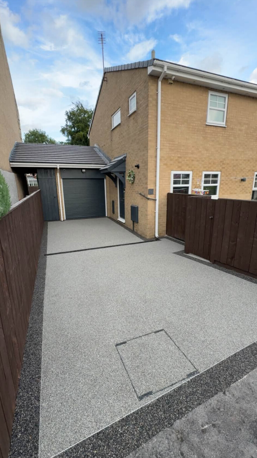 Resin-bound driveway with dark border leading to a garage in Carlisle